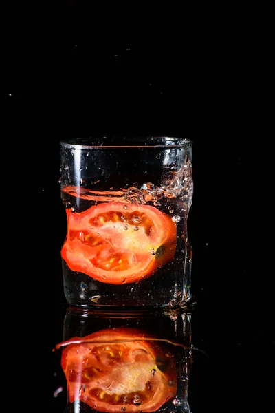 Bicchiere Acqua Uno Sfondo Scuro Acqua Spruzzata Con Pezzo Pomodoro — Foto Stock