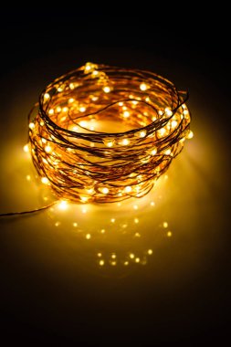 Yellow colored light chain for decoration placed on a reflective surface. Portrait view clipart