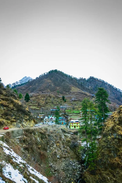 雪地上覆盖着树木和房屋的山谷 背景是雪峰蓝天的山 — 图库照片