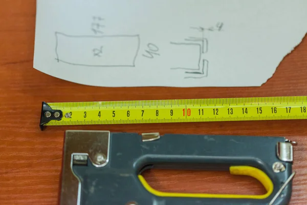 drawing with calculations and yellow metric measuring tape on the table, close up, blurry background