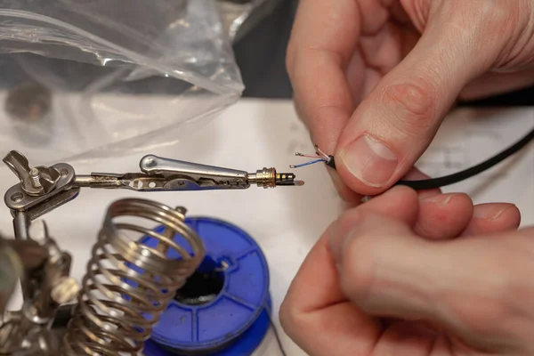 electrician repairing electrical component, on the table with the device and tools, close up, blurry background