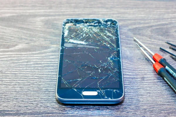broken cell phone on a table with tools ready for repair