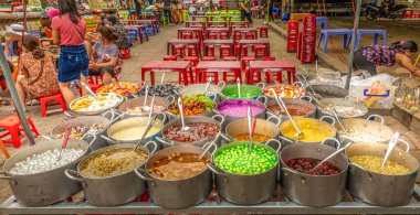 Hue / Vietnam - 08 Mart 2019: Satıcı sokak kenarındaki bir restoranda müşterilere yemek servisi yapıyor.