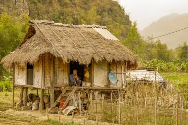 Mai Chau / Vietnam - 09 Mart 2019: Akşam ışığında evinin önünde oturan yaşlı bir adam.