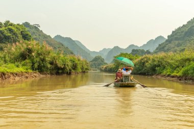 Tam Coc, Ninh Binh, Vietnam 'ın güzel manzarasını keşfeden kürek çeken turistler.