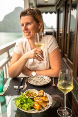 Halong Körfezi / Vietnam - 13 Mart 2019: Bir yolcu gemisinde güzel bir şarapla börek yemek.