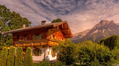 Ellmau / Avusturya - 05 Ağustos 2019: Günbatımında arkasında Wilder Kaiser olan geleneksel bir ev.