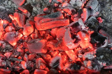 Aktif olarak yanan ateş közleri. Kömür yangınının dokusu. Yanan kömürlerin arka planı. Geceleri yanan kömürlerin titreşimi