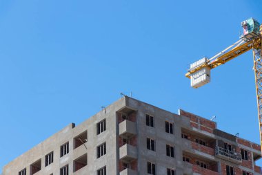 Mavi gökyüzüne karşı inşaat halindeki vinç ve binalar. Sanayi teması