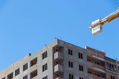 Mavi gökyüzüne karşı inşaat halindeki vinç ve binalar. Sanayi teması