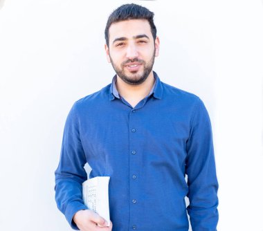 Elinde kitap tutan Arap adam.