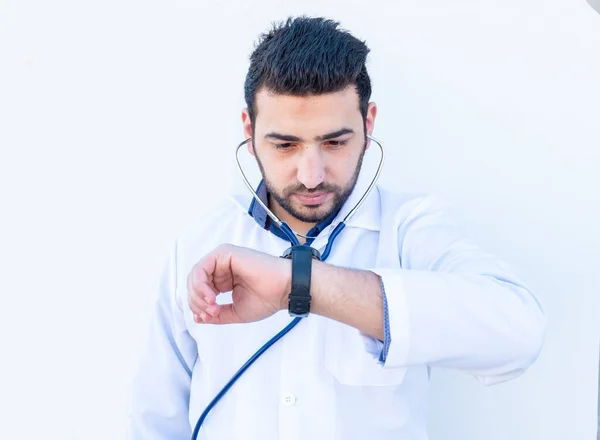Arabic doctor measuring pulse rate by his watch and listening to stethoscope