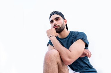 Adam dizinin üstüne çöküp bir şey izliyor.