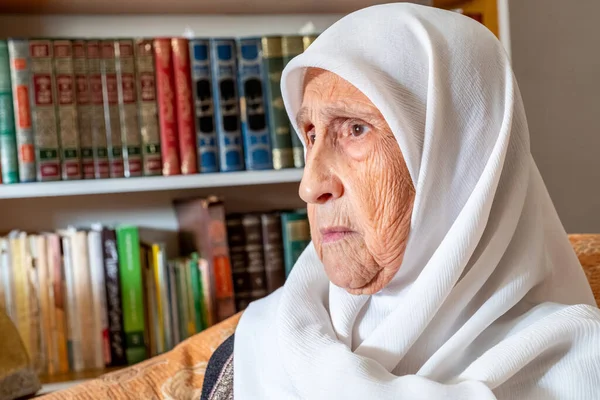 Arabic muslim old woman sitting on couch and feeling upset