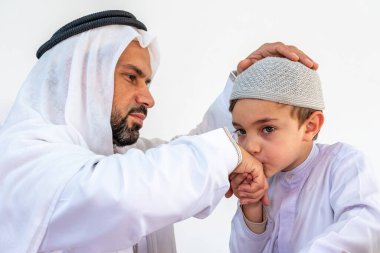 Arap Müslüman çocuk babasının elini öpüyor.
