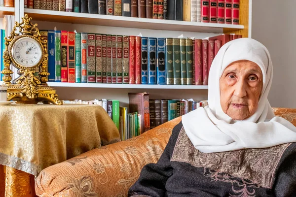 Arabic muslim old woman sitting on couch smiling
