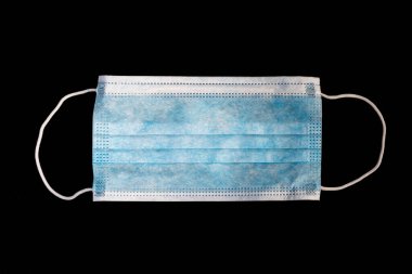 Tıbbi maske koyu bir geçmişi olan eller tarafından tutulur.