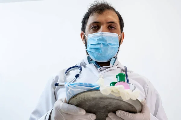Arabic muslim doctor wearing mask and presenting hygiene and protection products
