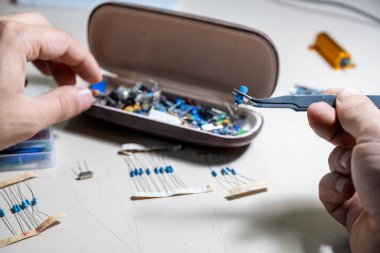 Elleriyle elektronik parçaları tutan adam.
