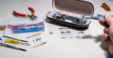Elleriyle elektronik parçaları tutan adam.