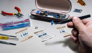 Elleriyle elektronik parçaları tutan adam.