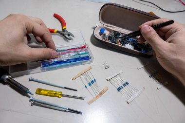 Elleriyle elektronik parçaları tutan adam.