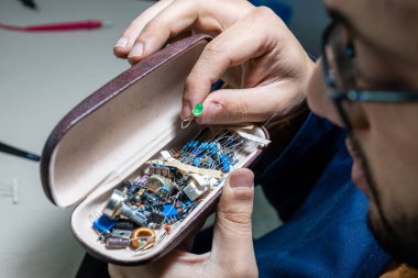 Elleriyle elektronik parçaları tutan adam.
