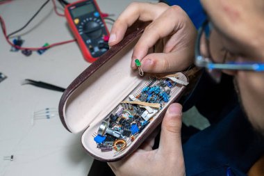 Elleriyle elektronik parçaları tutan adam.