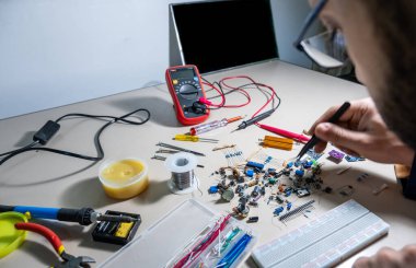 Elleriyle elektronik parçaları tutan adam.