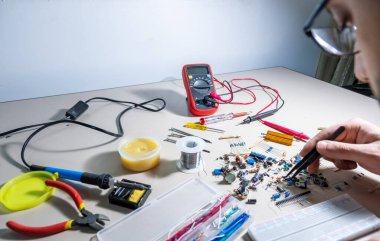 Elleriyle elektronik parçaları tutan adam.
