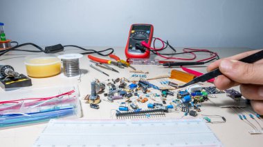 Elleriyle elektronik parçaları tutan adam.