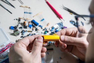 Elleriyle elektronik parçaları tutan adam.