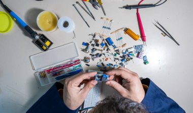 Elleriyle elektronik parçaları tutan adam.