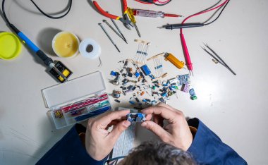 Elleriyle elektronik parçaları tutan adam.