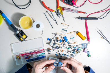 Elleriyle elektronik parçaları tutan adam.