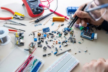 Elleriyle elektronik parçaları tutan adam.
