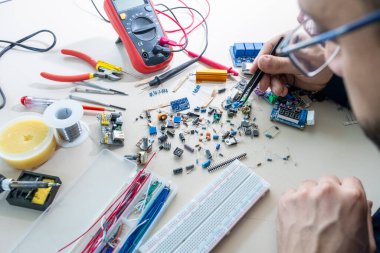 Elleriyle elektronik parçaları tutan adam.