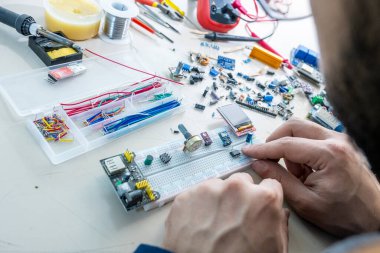 Elleriyle elektronik parçaları tutan adam.