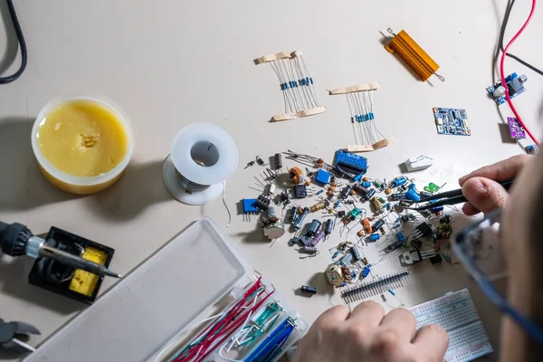 Elleriyle elektronik parçaları tutan adam.