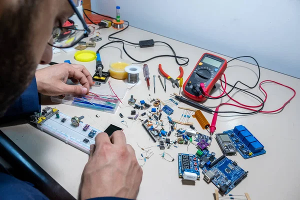 Elleriyle elektronik parçaları tutan adam.