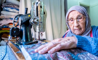 Arap Müslüman kadın eski dikiş makinesi kullanıyor.