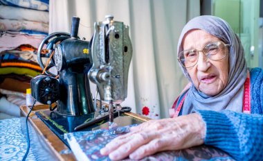 Arap Müslüman kadın eski dikiş makinesi kullanıyor.