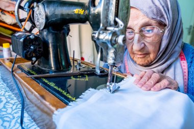 Arap Müslüman kadın eski dikiş makinesi kullanıyor.