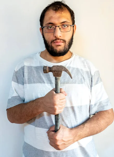 Arabic man holding a hammer infont of his chest