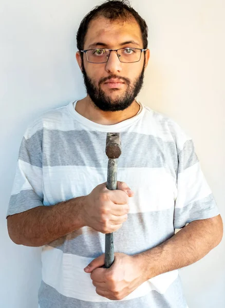 Arabic man holding a hammer infont of his chest