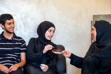 Mutlu Arap ailesi birlikte oturup Arap kahvesi, şeker ve birbirleriyle konuşuyorlar.