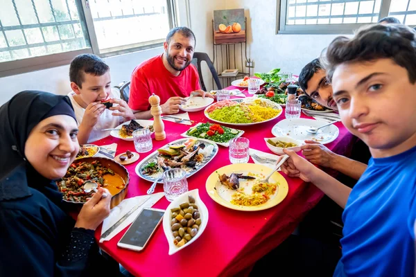 Arap çocuk telefonuyla selfie çekiyor. Ailesi de yemek için toplanıyor.