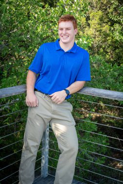 Handsome, red- headed young man posing for his High School graduation photos. Very attractive and athletic looking young boy.