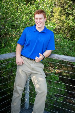 Handsome, red- headed young man posing for his High School graduation photos. Very attractive and athletic looking young boy.