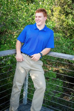 Handsome, red- headed young man posing for his High School graduation photos. Very attractive and athletic looking young boy.